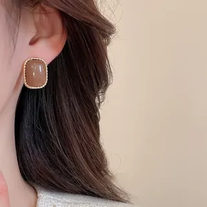 Detailansicht von Vintage-Ohrstecker aus braunem Harz mit goldenem Perlenrand am Ohr