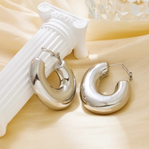Close-up of polished silver thick C-shape hoop earrings on elegant silk and stone