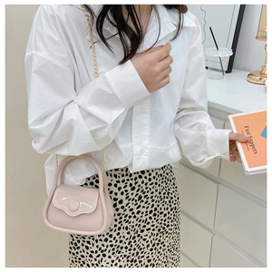 Pale pink mini PVC jelly bag with gold chain strap shown on model in urban outfit