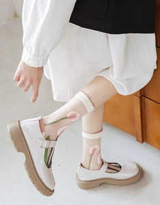 Détail de chaussettes blanches transparentes à motif tulipe rose et bordure en dentelle