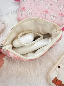 Pink quilted makeup bag with cute rabbit and flower patterns shown holding personal items