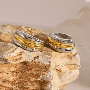 Detail shot of two-tone wavy stainless steel earrings on a natural rock texture