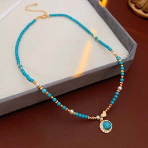 Détail du collier de perles turquoise avec pendentif coeur doré sur plateau velours