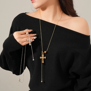 Detail shot of gold and silver cross pendant necklaces worn by a model in minimalist style