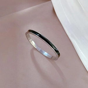 Close-up of a minimalist silver stainless steel open bangle with black enamel inlay