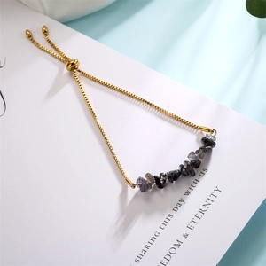 Detail of adjustable gold chain bracelet with dark gray irregular natural stones