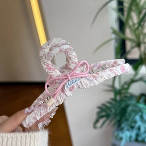 Detailsicht der Haarklammer mit Blumenmuster und einer rosa Schleife aus Stoff