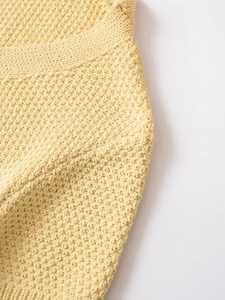 Detailed close-up of yellow knit cardigan showing textured wavy woven pattern and fabric