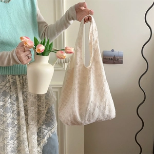 Detailed view of cream lace floral shoulder bag held by a model in a soft setting