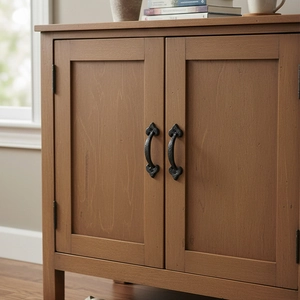 Vintage black cast iron door handles with hammer texture on a warm brown wooden cabinet
