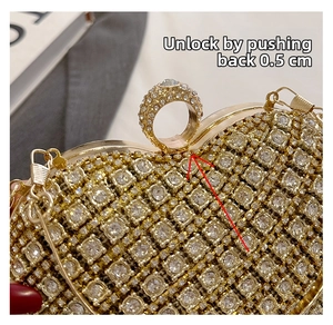 Detail of rhinestone heart clutch bag showing the gold finger ring clasp opening mechanism