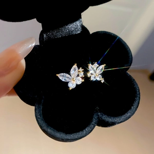 Macro shot of gold-plated butterfly stud earrings with sparkling zircon in a black box