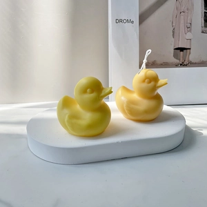 Nahaufnahme zweier gelber Enten-Bastelkerzen auf einem weißen Gips-Displayständer