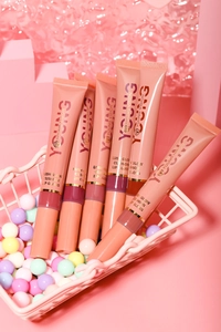 Six shades of glossy lip gloss displayed in a pink candy-filled mini shopping basket
