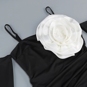 Detail of a large 3D white silk flower decoration on a black off-shoulder dress