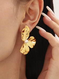 Nahaufnahme eines großen goldenen Sonnenblumen-Ohrrings mit Perle an einem Model