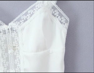 Close-up of white satin camisole featuring delicate lace trim and adjustable straps