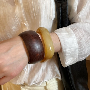 Detail view of wide resin and wood style bangles in amber and brown tones