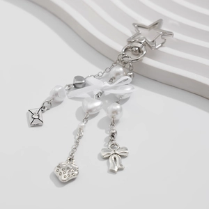 Close-up of bow keychain with stars, pearls and metal charms on wavy background
