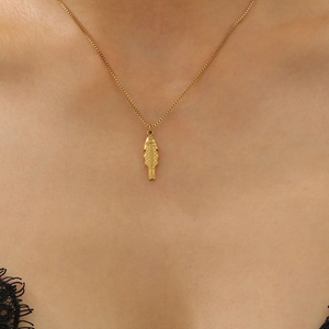 Close-up of a minimalist gold fish pendant necklace worn on a mannequin neck
