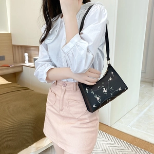 Chic black shoulder bag for women with elegant floral embroidery shown in a lifestyle setting