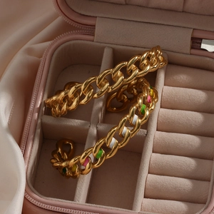 Detail of gold Cuban chain bracelet with colorful enamel drip on a pink jewelry box