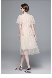 Detail of light beige mesh dress featuring polka dots and tiered ruffle cake skirt