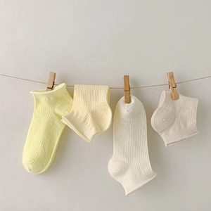 Minimalist cotton crew socks in pastel cream colors hanging on a rustic hemp rope