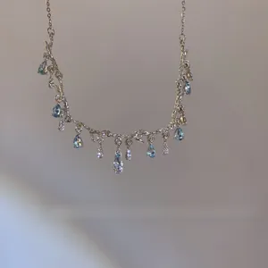 Detailed view of silver branch necklace with light blue pear-cut gems and tassel details