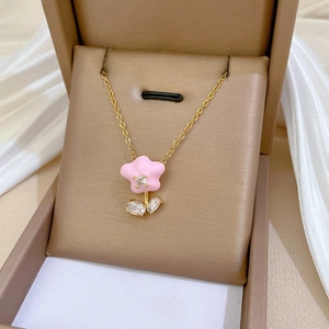 Close-up of pink flower pendant with zircons and gold chain in a jewelry box