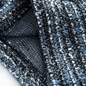 Vue macro montrant la texture épaisse du tissu en tweed tissé bleu, blanc et noir