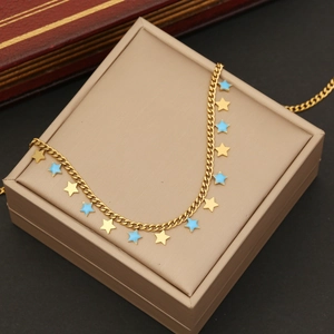 Macro shot of gold-plated necklace with blue and gold star charms in a beige jewelry box