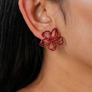 Détail de boucles d'oreilles fleurs rouges évidées avec laque métallique et pétales
