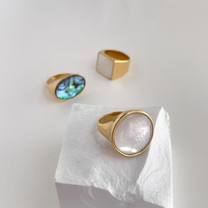 Detailed macro of gold geometric rings set with natural white and abalone shells