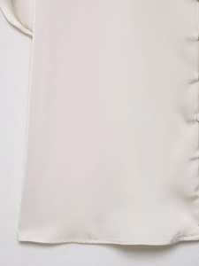Detailaufnahme des cremeweißen V-Ausschnitt-Oberteils mit Satin-Stoff und feinen Nähten
