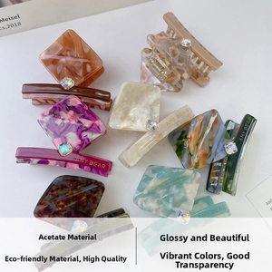 Detail of colorful marble acetate hair claws with square rhinestone and gold branding
