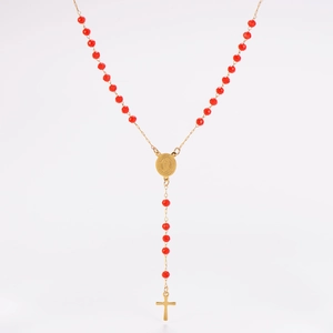 Détail de perles rouges à facettes avec crucifix et médaille dorés sur fond blanc