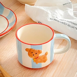 Nahaufnahme der blau gestreiften Keramiktasse mit braunem Welpen-Relief und rotem Rand