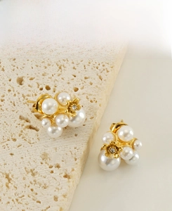 Macro shot of irregular floral pearl earrings with gold base on a textured stone