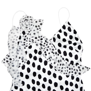 Dettaglio di abito a pois bianco e nero con elegante fiore a balze asimmetrico sulla spalla