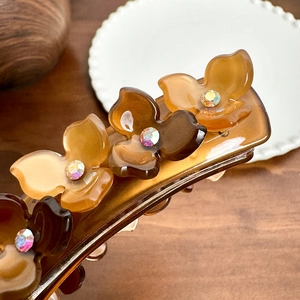 Elegant tortoise shell hair clip with crystal flower accents for a stylish ponytail look