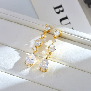 Macro detail of elegant gold drop earrings featuring teardrop and oval shaped zircons