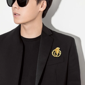 Detailed close-up of a vintage golden snake brooch with green and blue crystals on a lapel