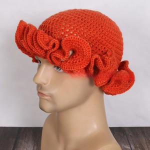 Detailed close-up of orange ruffle knit beanie hat showing crochet texture and wavy brim