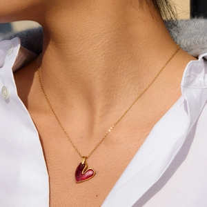 Dettaglio di una collana vintage placcata oro con pendente a cuore in smalto rosso su modella