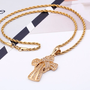Close-up of golden twist chain with iced-out cross pendant featuring knotted design