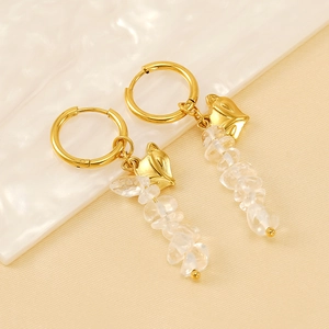 Golden fox face earrings with natural white crystal stone pendants on marble background