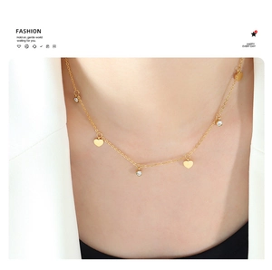 Close-up of golden heart and zircon pendant necklace on collarbone with white blazer