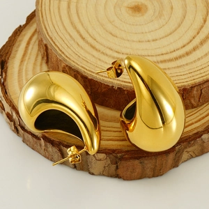 Polished 18K gold-plated teardrop earrings on wood background, minimalist fashion style