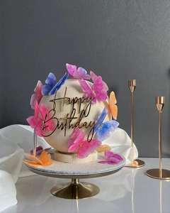 Detailed view of pink and blue butterfly cake toppers with golden Happy Birthday sign